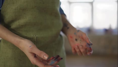 Female-painter-standing-covered-with-dirty-hands-after-artwork-done