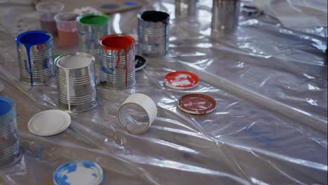 Overview-of-paint-cans-on-floor-at-industry,-high-angle-circling-shot-of-containers-at-workshop