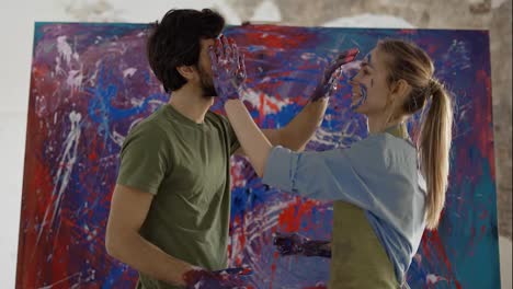 Pair-in-love-painting-each-others-faces-standing-in-front-large-canvas