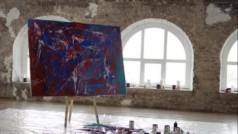 Emotional-modern-picture-in-bright-creative-studio-large-canvas-stands-on-easel