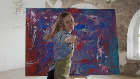 Female-artist-emotionally-dancing-in-front-of-abstract-painting-in-studio