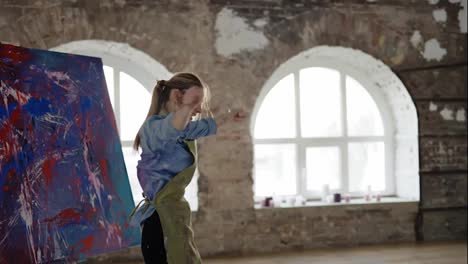 Artista-Femenina-Bailando-Emocionalmente-Frente-A-La-Pintura-Abstracta-En-Estudio-En-Cámara-Lenta