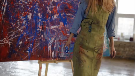 Portrait-female-painter-after-finishing-her-masterpiece-in-art-studio