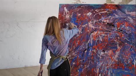Woman-drawing-abstact-picture-using-spraying-paints-in-art-studio