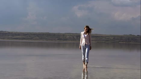 Alone-young-woman-in-casual-is-walking-on-shallow-of-lake-at-summer