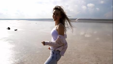 Beatiful-girl-by-the-lake-on-the-shore,-running-and-walking-on-shore,-making-fun