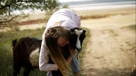 Woman-stroking-goat-outdoors,-caresses-it-with-both-hands