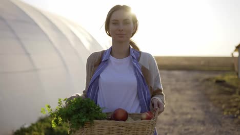 Happy-farmer-showing-basket-with-fresh-harvested-vegetables-and-smiling-in-camera-on-countryside
