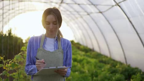 Joven-Agricultora-En-Invernadero-Interior,-Plantas-Contables-Usando-Tableta