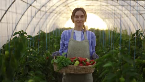 Portrait-of-a-woman-with-fresh-harvested-greens-and-peppers-in-greenhouse