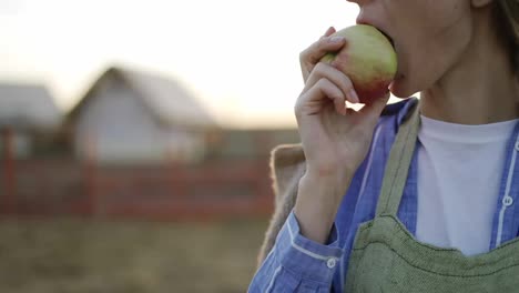 Young-woman-biting-a-ripe-red-apple.-Organic-food-and-gardening-concept