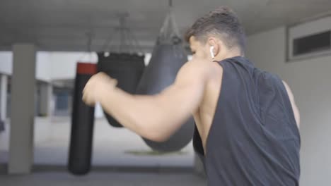 Martial-art-fighter-does-shadowboxing,-kickboxer-training-strikes-in-gym