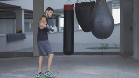 Entrenamiento-De-Kickboxer-Masculino-Muscular-En-Diferentes-Tipos-De-Bolsas-De-Boxeo