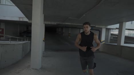 Athlete-runs-around-by-levels-of-and-empty-parking-garage,-front-view