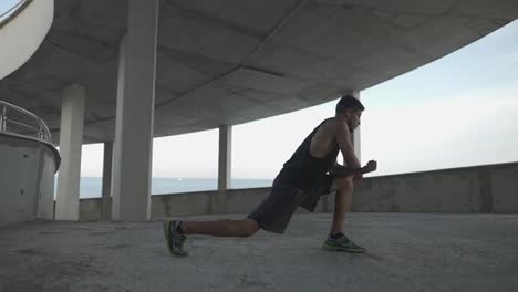 Athlete-in-sportswear-warms-up-on-a-city-parking-garage,-stretching-legs