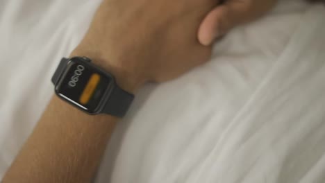 People,-bedtime-and-rest-concept---close-up-of-man-with-smartwatch-sleeping-in-bed