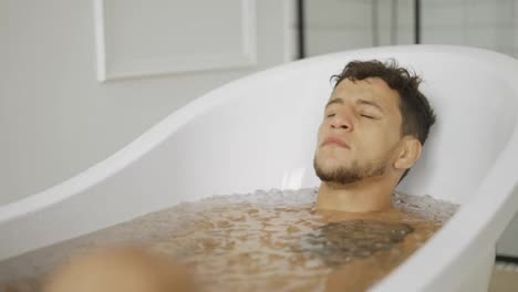 Man-sits-with-closed-eyes-in-the-bath-with-ice-cubes-for-recovery