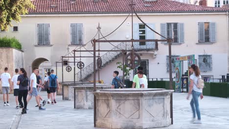 A-group-of-teenagers-on-tours-visiting-the-Five-Wells-square-in-Zadar,-Croatia