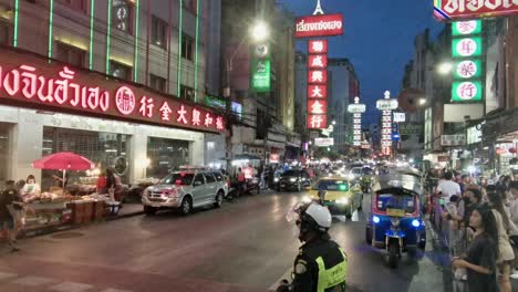 Policeman-Watching-Traffic-in-Chinatown-at-Night-with-Illuminated-Lights-in-Bangkok,-Thailaand