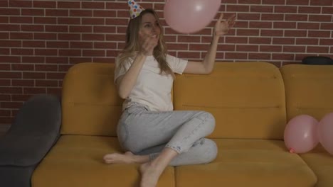 Frau-Mit-Geburtstagshut-Im-Dekorierten-Raum,-Die-Ballon-Spielt
