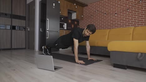 Man-athletic-trainer-doing-push-up-at-home-live-teaching-via-laptop-or-video-call