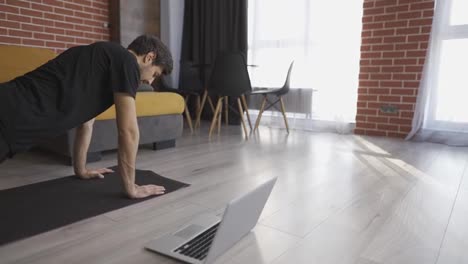 Young-man-doing-plank-exercise-with-online-tutorial-at-home