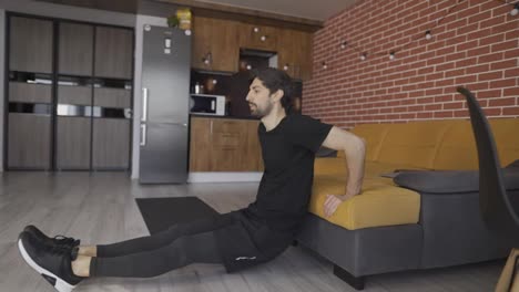 Man-athletic-doing-push-up-leaning-on-sofa-at-home