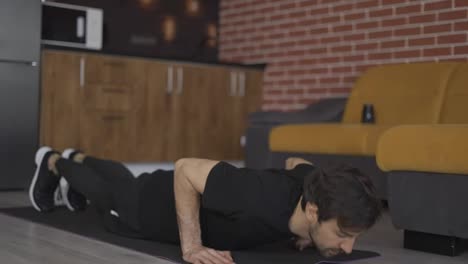 A-european-man-works-out,-doing-push-ups,-lying-on-a-mat-at-home