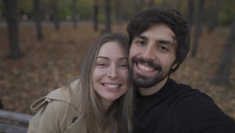 Love-couple-making-selfie-on-a-bench-in-the-park-at-autumn-fall-season
