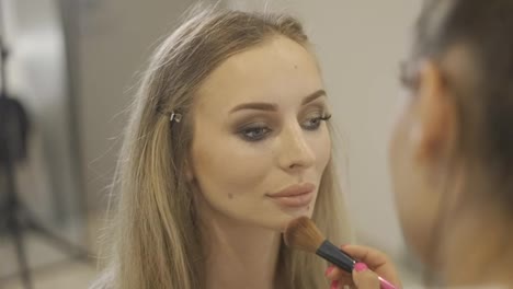 The-make-up-artist-applies-the-powder-to-finish-client's-makeup