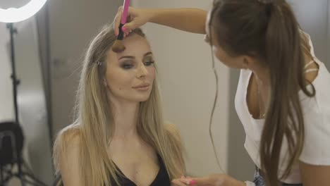 The-make-up-artist-applies-the-powder-to-finish-client's-makeup-at-bright-studio,-slow-motion