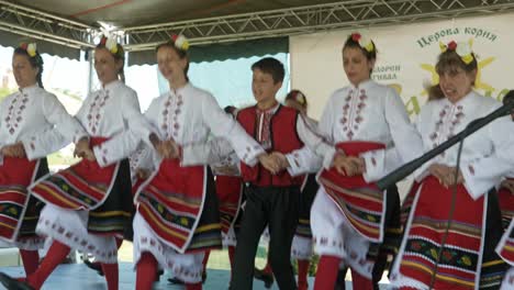 Happy-smiling-performers-in-traditional-dress-dancing-Bulgarian-horo-on-stage