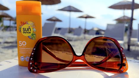 Nahaufnahme-Einer-Sonnenbrille-Und-Sonnencreme-Auf-Einem-Strandtisch