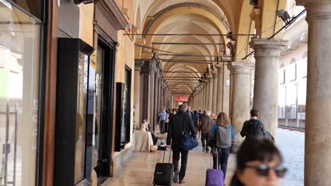 Archway-at-Via-dell-Archiginnasio-street-a-lot-of-people-and-tourists-in-Bologna,-Italy