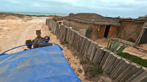 Unusual-overhead-slow-motion-view-of-a-horse-drawn-carriage-with-man-and-woman-along-Tunisian-seaside-village-in-Tunisia