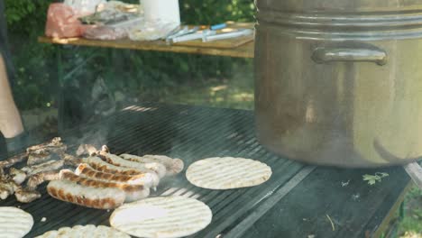 Chef-cooks-pork-meats-and-pitta-breads-on-smoky-bbqvat-outdoor-festival