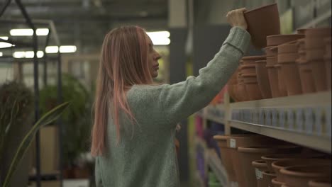 Woman-buying-clay-pot-for-home-plants-from-shelves-of-a-flower-shop