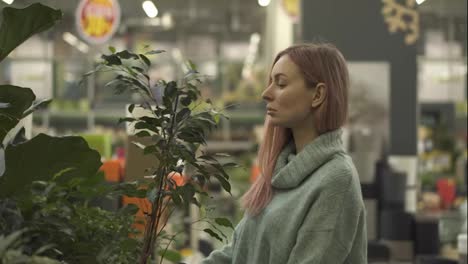 Blonde-woman-choosing-plants-at-flower-market-in-garden-shop