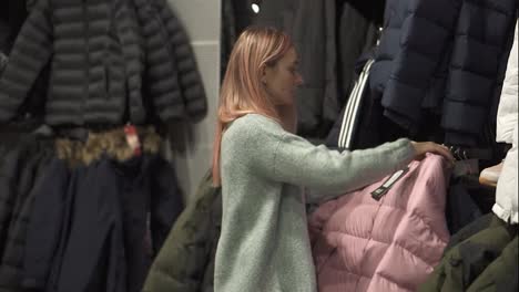 Woman-is-taking-a-new-winter-coat-from-a-rack-to-fit