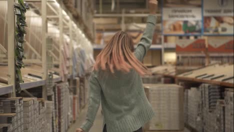 Longhaired-woman-dances-in-hardware-store-between-the-rows