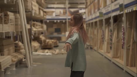 Relaxed-woman-dances-in-hardware-store-between-the-rows