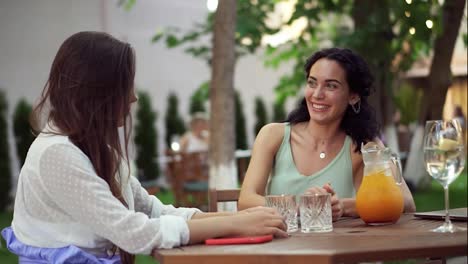 People,-communication-and-friendship-concept---smiling-young-women-drinking,-talking-at-outdoor-cafe,-brunette-sharing-good-news