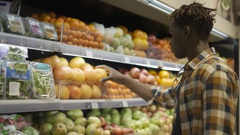 Afro-american-guy-choosing-oranges-from-the-fruits-aisle