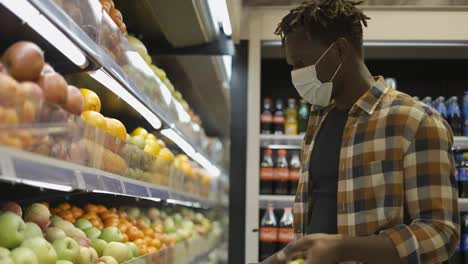 Afroamerikanischer-Mann-Steht-Im-Supermarkt-Und-Legt-Äpfel-In-Den-Einkaufskorb