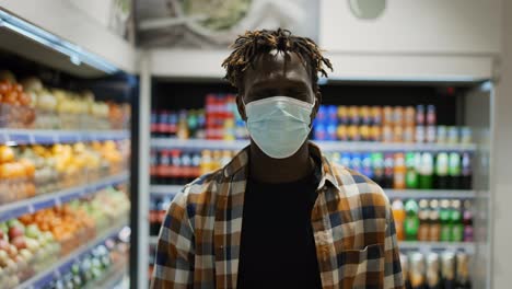 African-american-man-in-mask-walks-by-supermarket