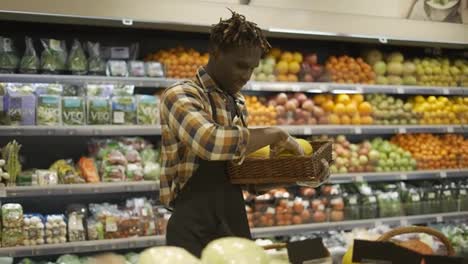 Grocery-worker-rearranging-storage-racks-in-fruit-department