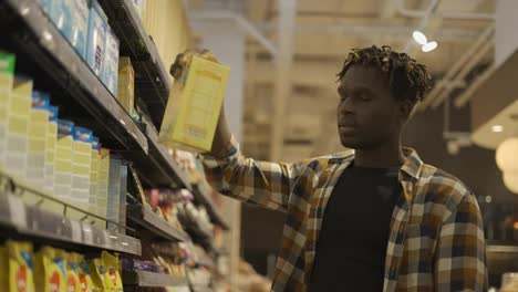 African-american-guy-chooses-products-in-the-grocery-store,-put-it-to-the-cart