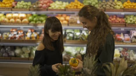 Two-caucasian-girls-choosing-bio-fruits---grape-in-supermarket-together