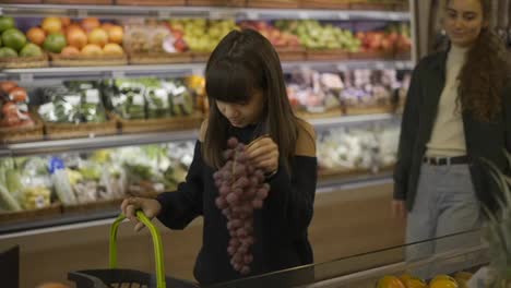 Schöne-Mädchen,-Die-Gemeinsam-Bio-Früchte---Trauben-Im-Supermarkt-Auswählen