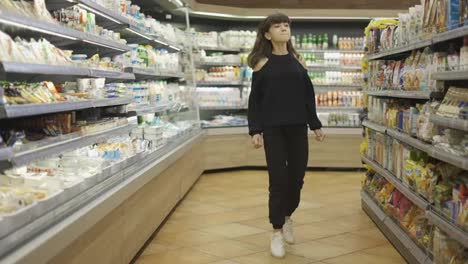 Independent-teenager-in-the-supermarket,-passing-by-food-sections